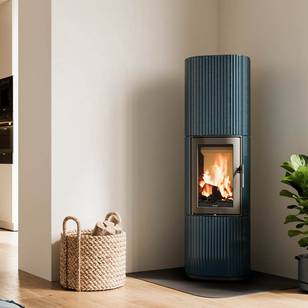 LEDA SANNA Speicherofen in Petrolblau mit emaillierter Gussoberfläche, geriffeltem Design und großzügiger Feuersicht.